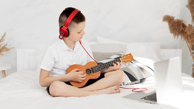 Free photo boy with headphones playing ukulele