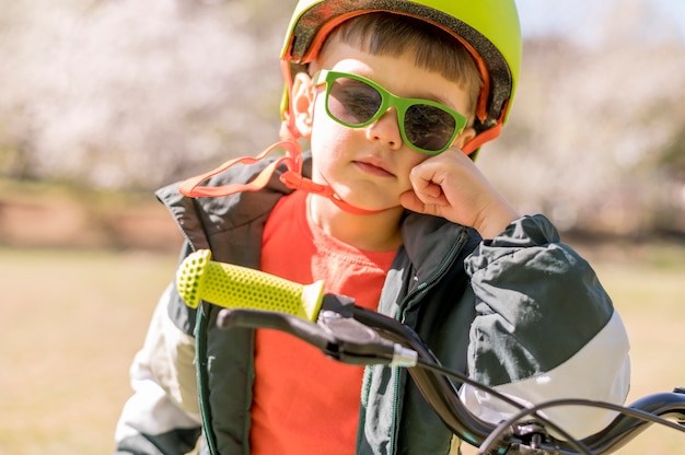 自転車に乗ってヘルメットを持つ少年