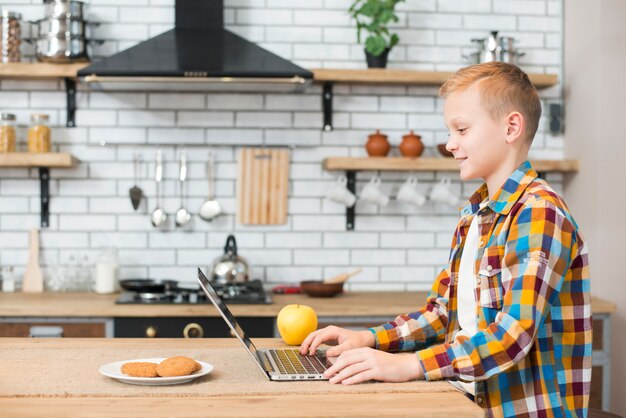 Foto gratuita ragazzo con il portatile in cucina