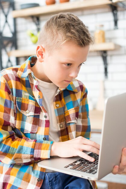 Boy with laptop in kitchen