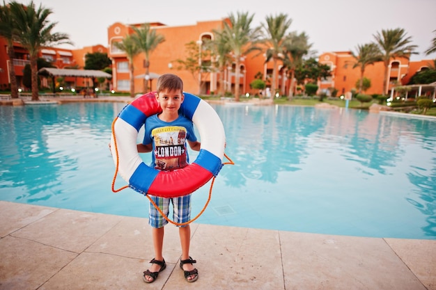 Бесплатное фото Мальчик со спасательным кругом стоит возле бассейна египетского курорта
