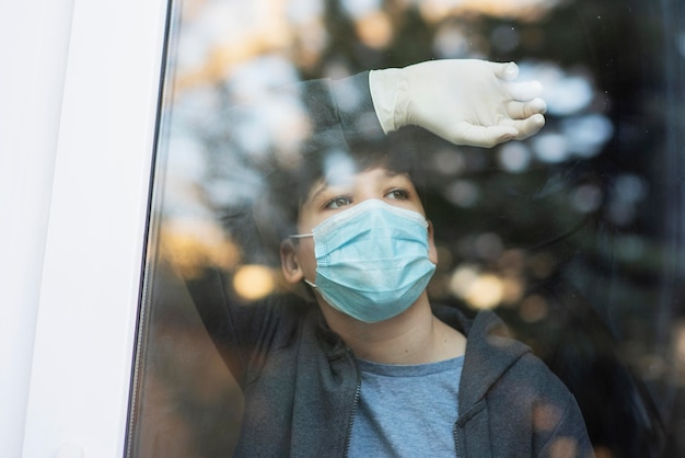 Free photo boy with medical mask looking outside