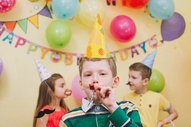 Boy with noisemaker on party with friends