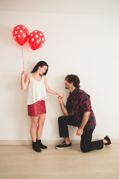 Free photo boy with one knee on the floor and holding his girlfriend's hand