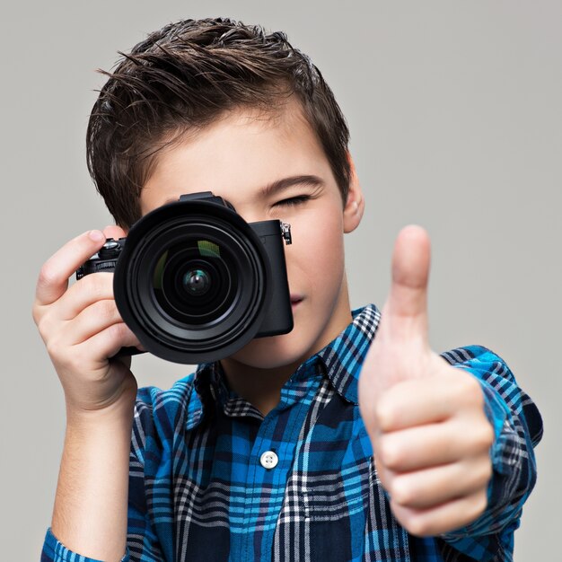 Boy with photo camera taking pictures. Teenager  boy  with dslr camera shows the thumb up