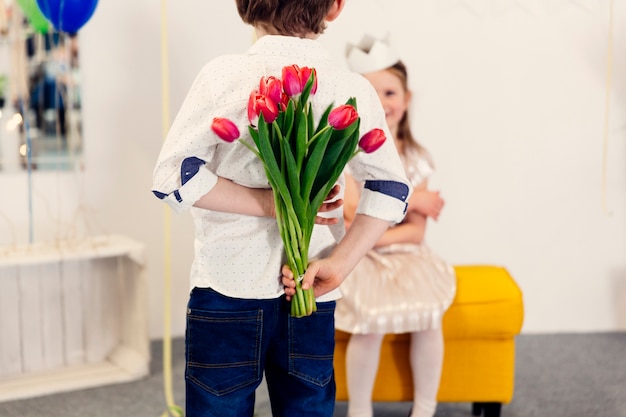 Boy with pink tulips behind