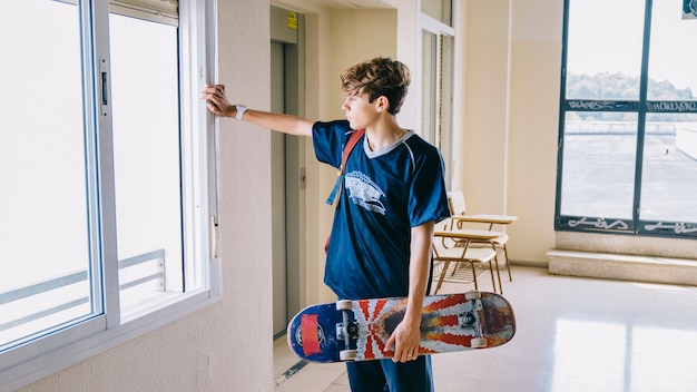 Boy with skateboard looking through window