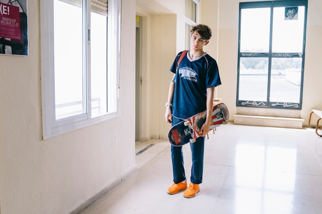 Boy with skateboard in school