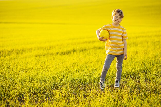 牧草地でサッカーボールを持つ少年