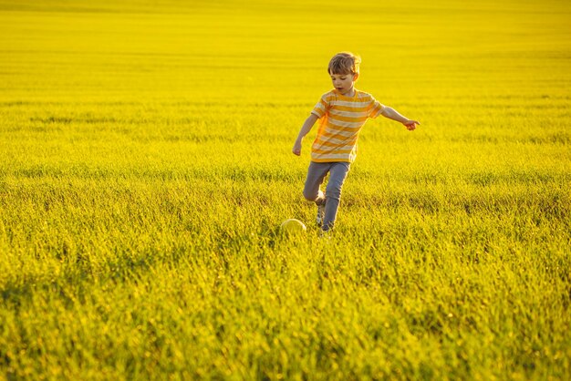 牧草地でサッカーボールを持つ少年