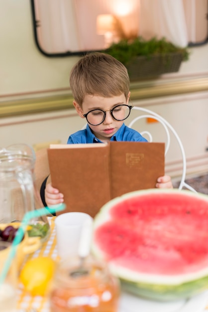 Free photo boy with sunglasses reading at the table