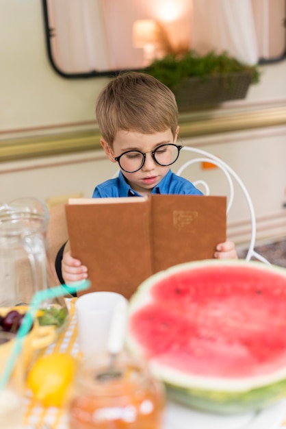 テーブルで読んでサングラスを持つ少年