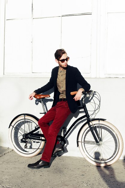 Boy with sunglasses and red trousers sitting on a bicycle