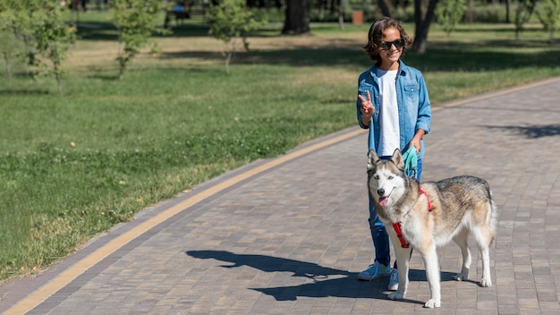 Boy with sunglasses walking his dog at the park