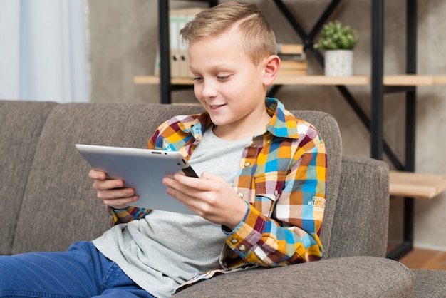 Free photo boy with tablet on couch