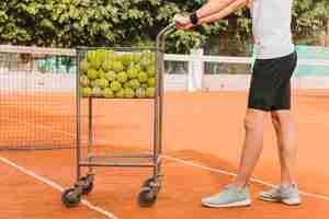 Foto gratuita ragazzo con carrello da tennis