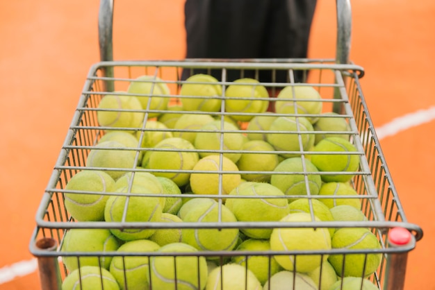 Free photo boy with tennis balls cart