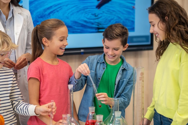 Boy with test tube and watching smiling girls