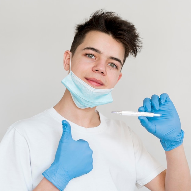 Boy with thermometer showing ok sign