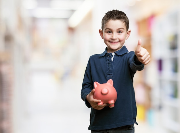 Boy with thumb up and a piggy bank