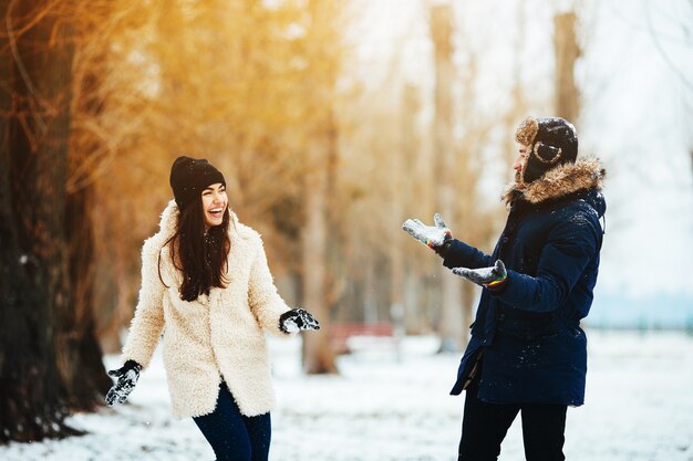少年と雪に覆われた公園で雪と遊ぶ女性