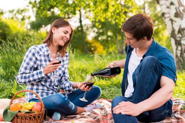 Boyfriend filling glasses held by girlfriend with wine