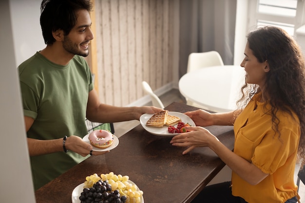 Free photo boyfriend and girlfriend eating waffles together at home