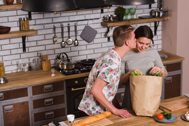 Парень целует женщину с продуктами