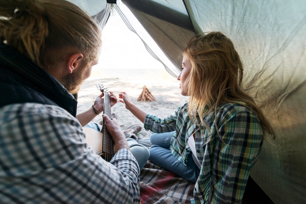 Free photo boyfriend playing acoustic guitar in tent side view