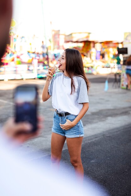 Boyfriend taking photo of girlfriend eating ice cream