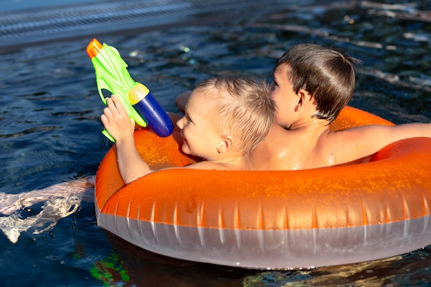 Ragazzi che si divertono in piscina con galleggiante e pistola ad acqua
