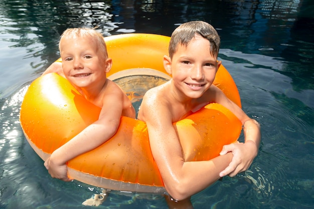 Boys having fun at the swimming pool with pool float