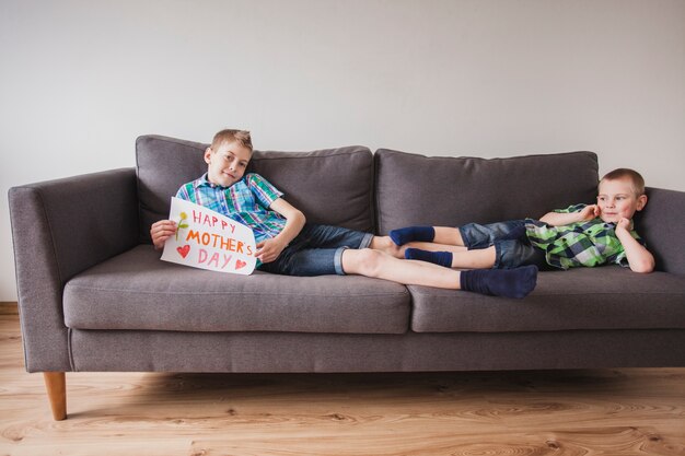 母親の日の看板でソファに横たわっている男の子