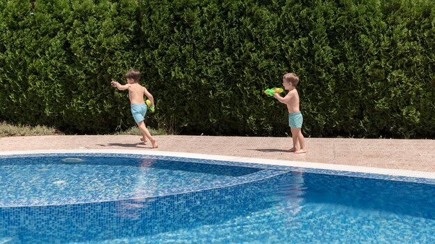 Boys at pool playing with water gun