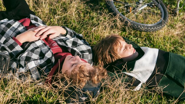 Boys resting on grass while riding their bicycles