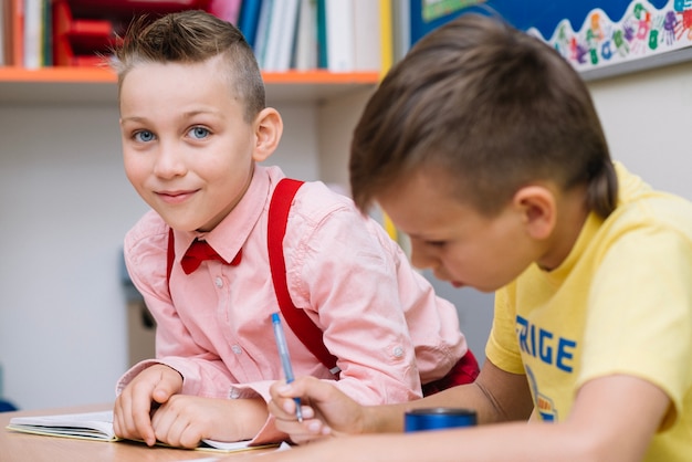 学校の机に座っている男の子