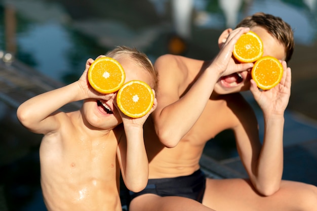 Мальчики у бассейна с апельсином