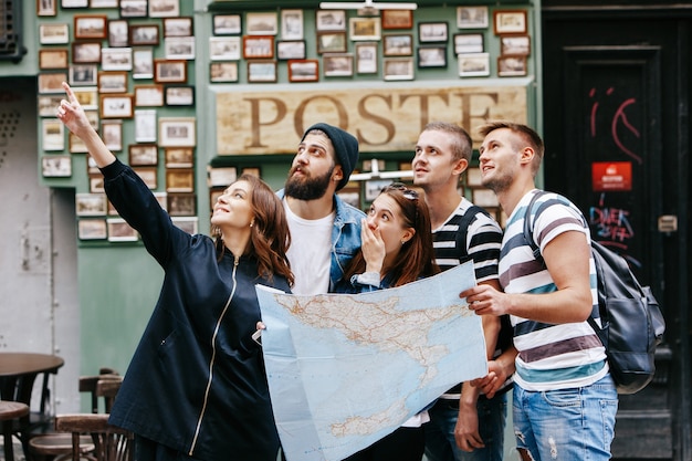 Ragazzi con borse e ragazze con una cartina turistica guardano qualcosa da qualche parte nella città vecchia