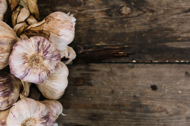 Braid garlic bulbs on wooden textured backdrop