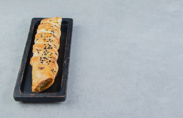 Braided bun stuffed with meat on black plate.