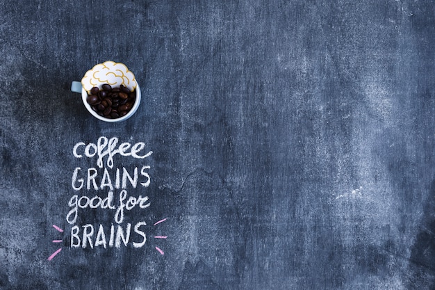 Brain paper cutout and coffee beans in cup with text on chalkboard