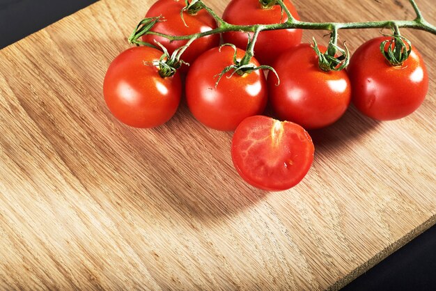 Branch of red cherry tomatoes organic wooden.