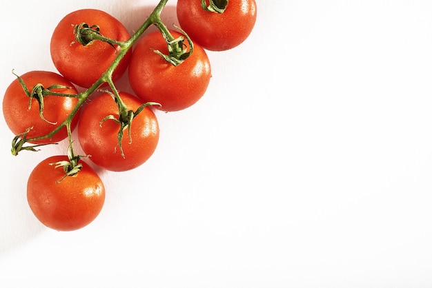 Branch of red organic tomatoes on a white.