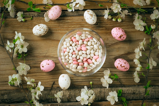 Branch Of Spring Flowers And Colorful Pink Candy Eggs For Easter On Rustic
