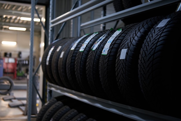 Brand new big variety of car's tyres on shelf with prices at store or warehouse.