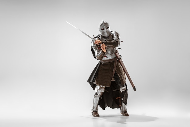 白いスタジオの背景に分離されたプロの武器の戦いを持つ勇敢な装甲騎士。戦士のネイティブの戦いの歴史的な再構築。歴史、趣味、アンティークの軍事芸術の概念。