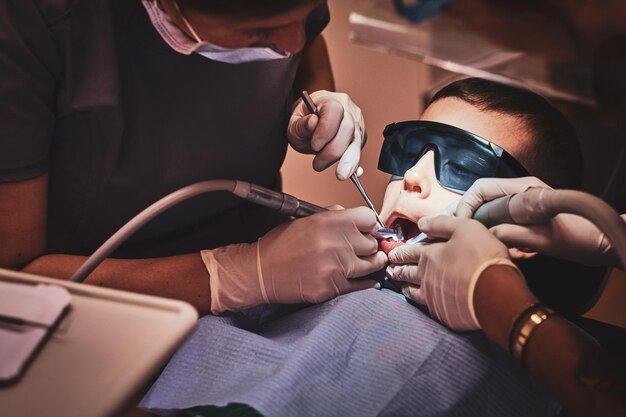 Brave small child gets a dental treatment by expirienced doctor at dental clinic.