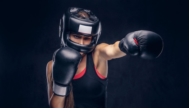 勇敢な女性は戦う準備ができています、彼女はボクサーの手袋と保護用のヘルメットを着用しています。