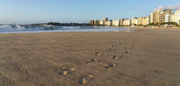 Brazilian beach with footprints in the sand and wild waves of the ocean on a sunny summer day