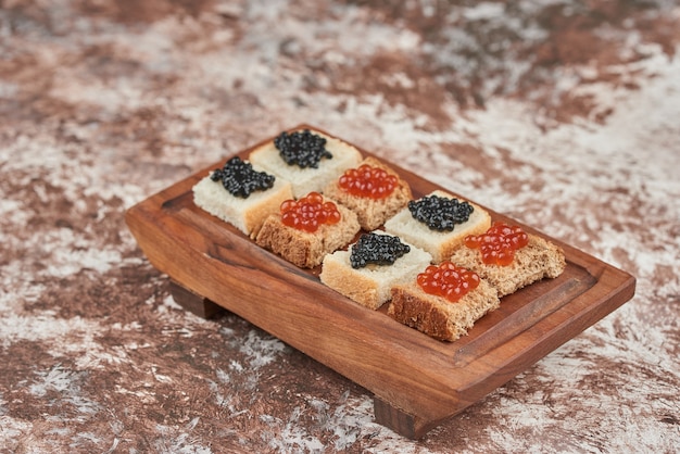 Free photo bread aperitifs on the marble with caviar on wooden board.